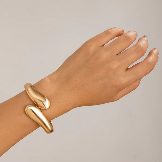 Bracelet manchette Eos doré porté au poignet, affichant un design minimaliste et audacieux, parfait pour une touche élégante et moderne.